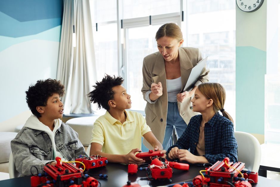 A teacher assists diverse students with a hands-on robotics project at school.