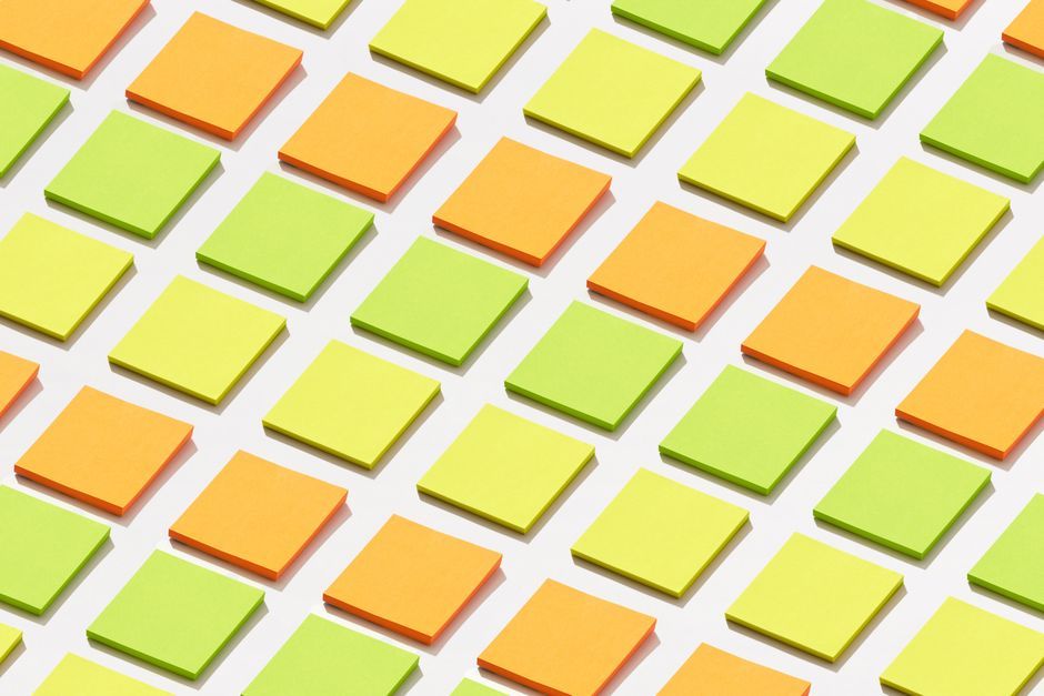 A vibrant arrangement of sticky notes in orange and green hues on a white background.