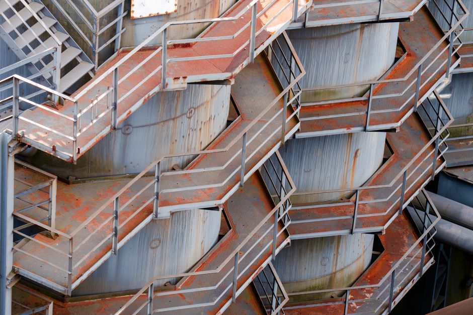 Detailed view of a rusty industrial staircase showcasing geometric patterns and metal texture.