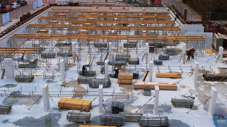 A busy construction site with scaffolding, steel structures, and workers.