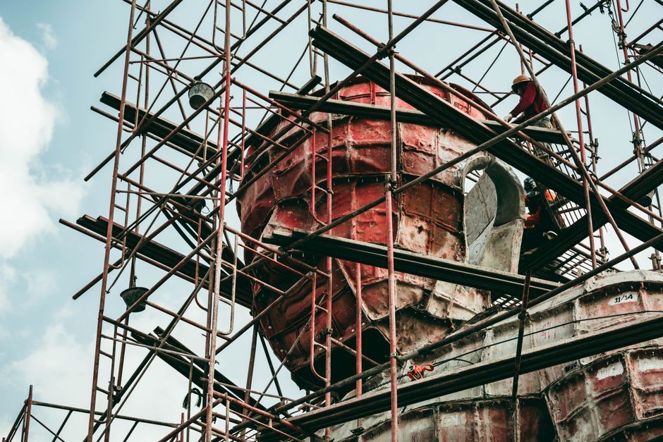 Workers on scaffolding during statue construction, showcasing building process.