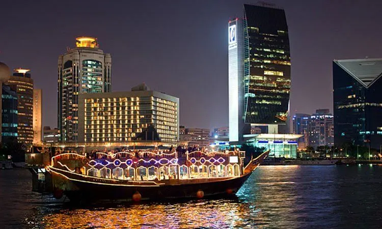 Dhow boat dinner cruise on Dubai Marina at night, enjoying city lights and traditional Arabian cuisine.