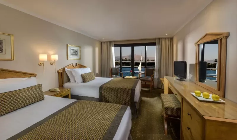 Luxurious cabin aboard Steigenberger Royale Nile Cruise – plush bedding and panoramic windows overlooking the river