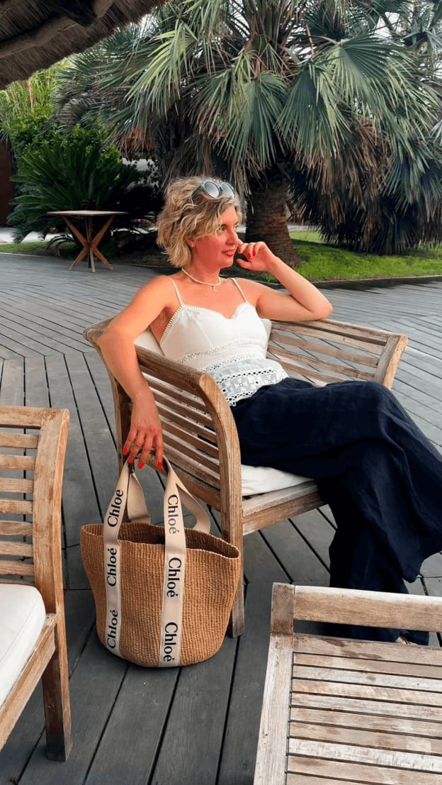 Donna seduta su terrazza con borsa fashion. Shooting lifestyle per strategia social media marketing.