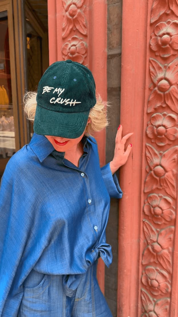 Donna con cappello verde davanti edificio storico. Shooting moda per personal branding e content marketing.