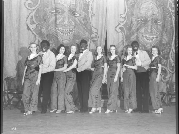 Group portrait of men dressed as minstrels posing with women dancers at the Moolah Temple