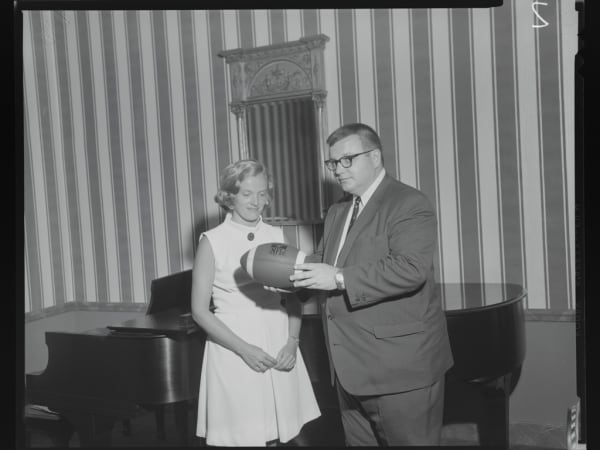 ST. LOUIS CARDINALS FOOTBALL PLAYER AND WOMAN POSING WITH A FOOTBALL AT THE POWELL SYMPHONY HALL.