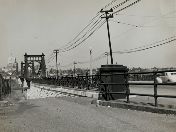 The Grand Avenue Bridge in 1946, seen from the sidewalk at one approach, with a tower portal at left and a downtown skyscraper beyond.