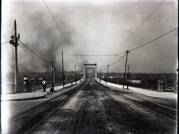 Looking down the deck of the Grand Avenue Bridge from Market Street, with streetcar tracks on both sides and a tower portal in the distance.