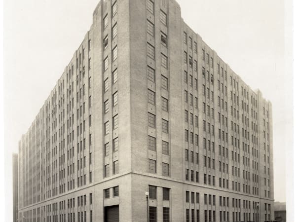 The newly built International Shoe Company annex, with stepped Art Deco caps on the corner piers, a loading door at the corner and cars parked along both streets.