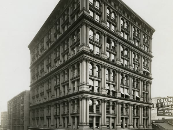 The Equitable Building after its five-story addition, with storefronts and awnings on Sixth Street and the Columbia Theatre sign beyond.
