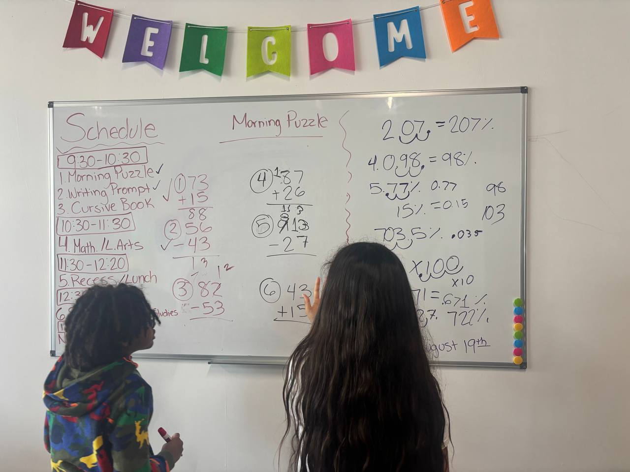 Homestead microschool students solving morning math puzzles at the whiteboard