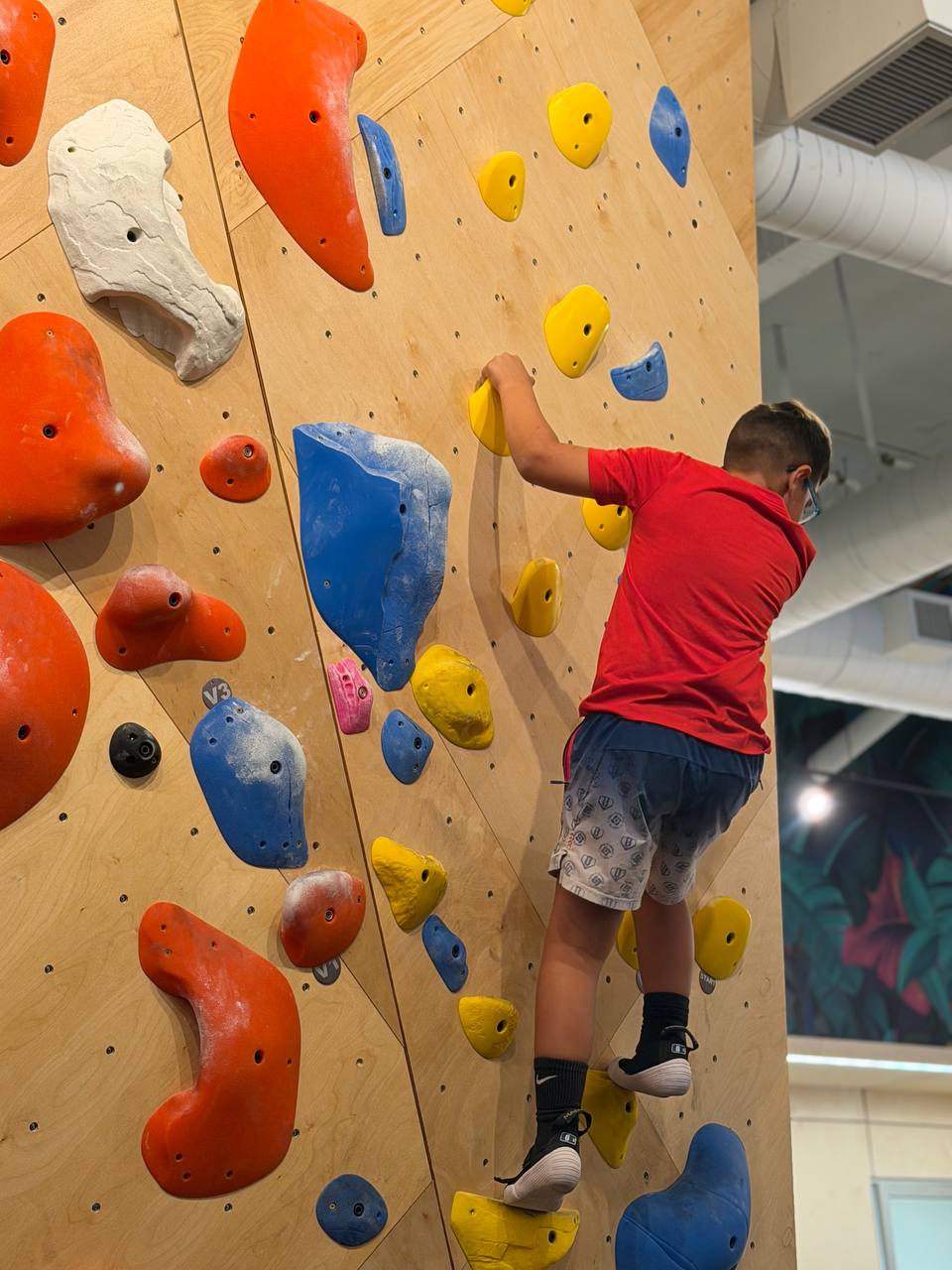 A Pinecrest microschool student bouldering on the climbing wall during movement time