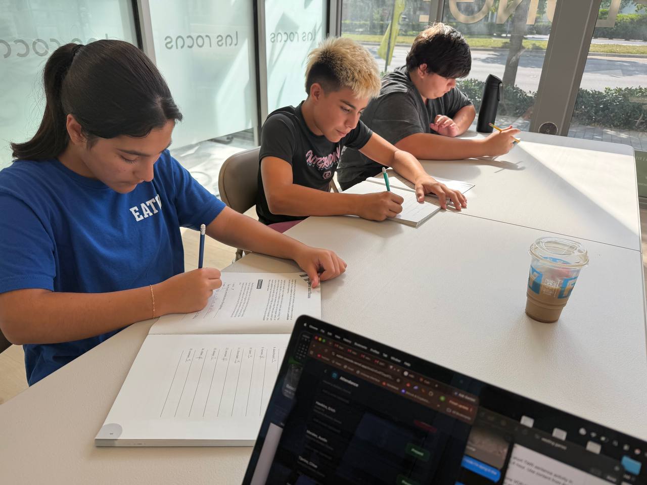 Eaton students writing exercises together at a table inside Las Rocas Climbing in Pinecrest