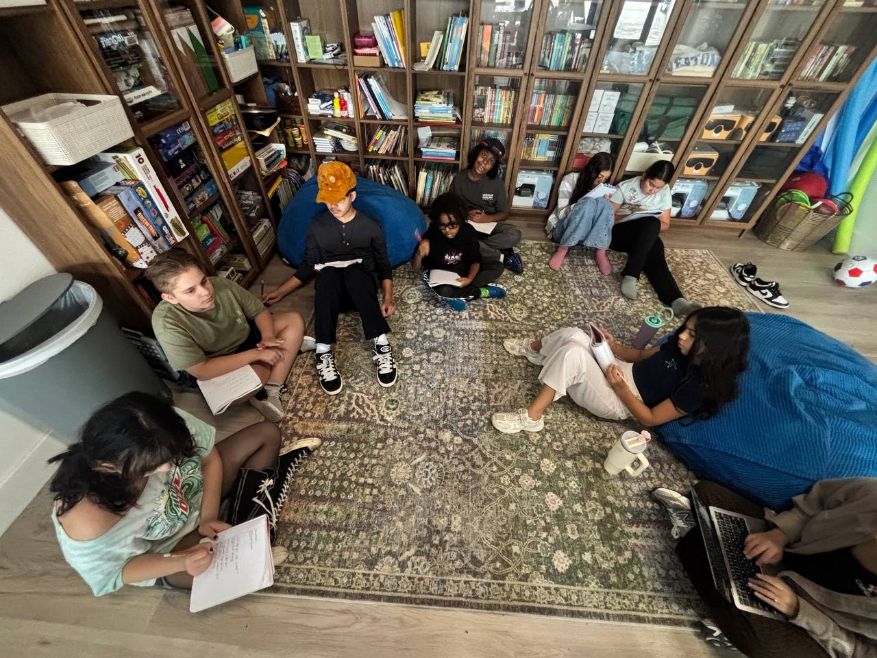 Homestead microschool students reading and writing on the rug in the Eaton library corner