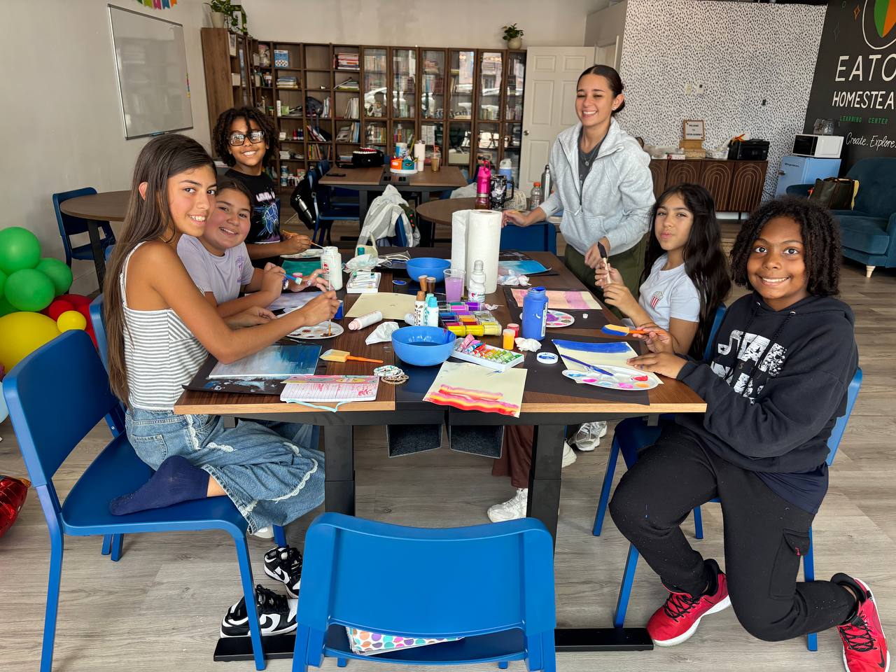 Eaton Homestead microschool students painting together with their teacher at the learning center