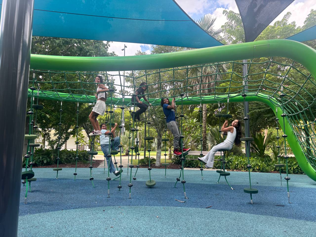 Eaton Homestead students climbing a rope net at a shaded park during recess