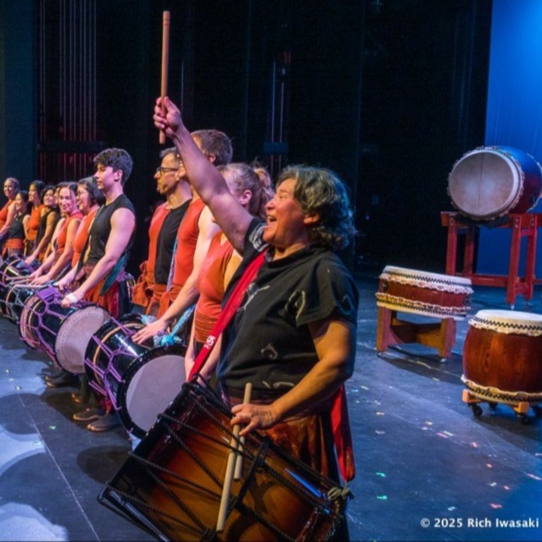 Taiko players with drums slung over their shoulders line up to take a bow