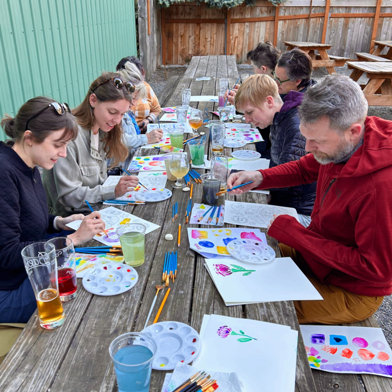 People painting and enjoying beverages on the back patio of Baerlic Brewing