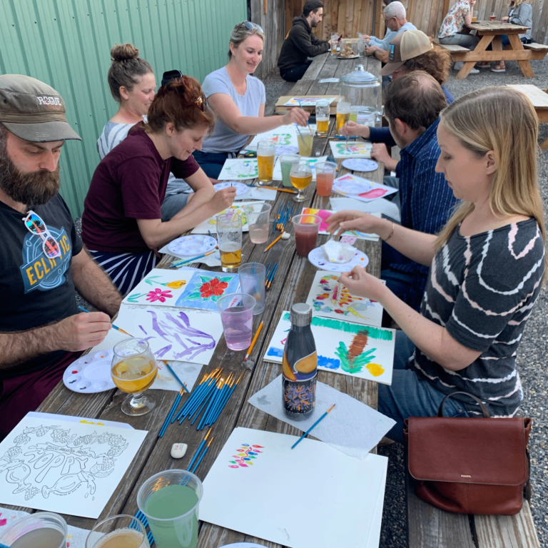 People painting and enjoying beverages on the back patio of Baerlic Brewing