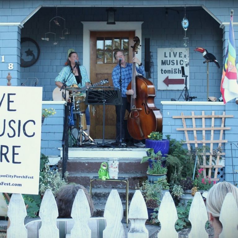 two people playing instruments on a porch during a festival