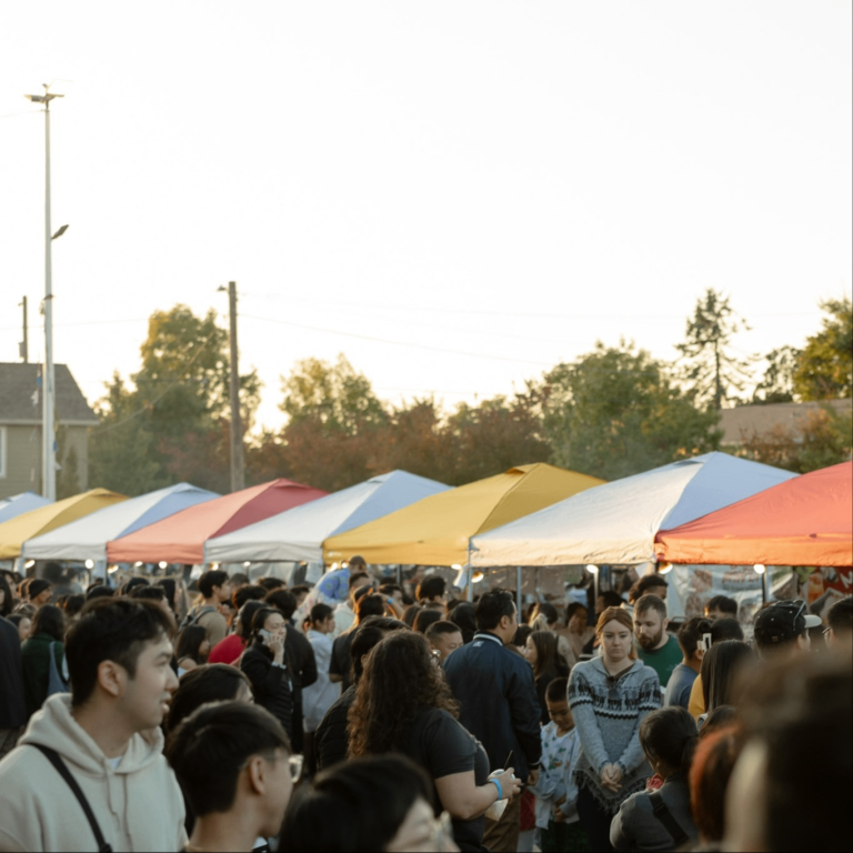 crowds of people browsing booths at an open air market
