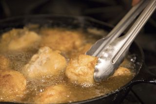 chicken being fried in a cast iron skillet