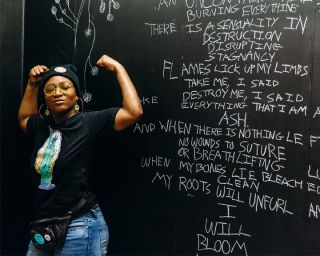 person poses in front of a mural wearing a dfrntpigeon t-whirt