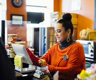 Woman at the till of a coffee house ringing up an order.