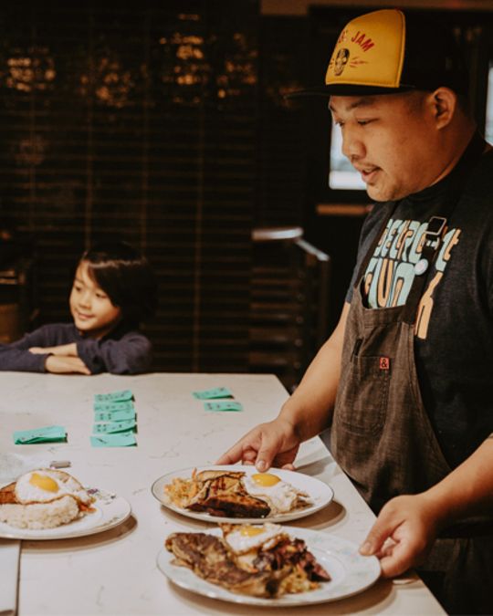 Chef Carlo Lamagna reviews dishes with his child at a Magna pop-up.