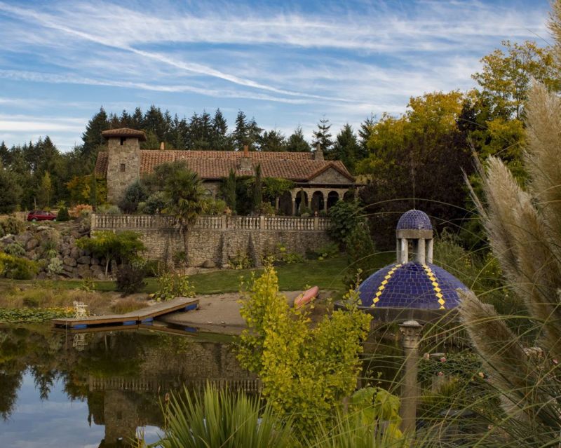 View of large stone house overlooking a vineyard and a pond
