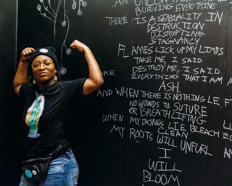 person poses in front of a mural wearing a dfrntpigeon t-whirt