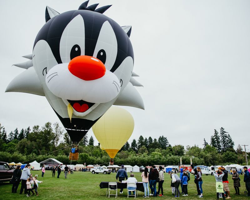 a sylvester the cat shaped hot air balloon sits against a grey sky