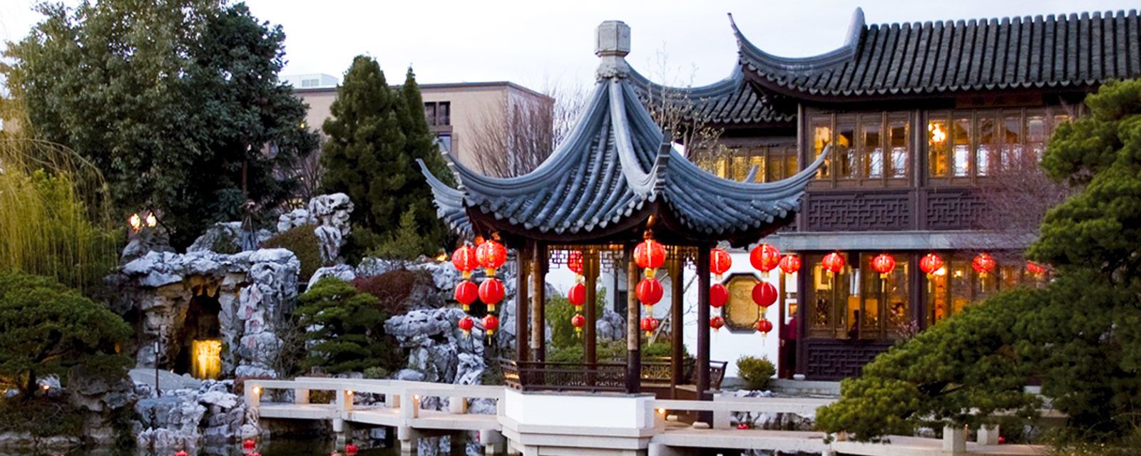 red lanterns float in water in front of a Chinese-style building