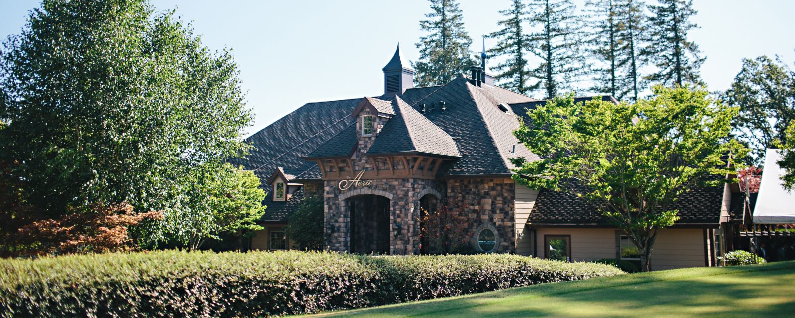 Exterior of a brick building with Aerie logo above the front door and sprawling gardens leading up to it