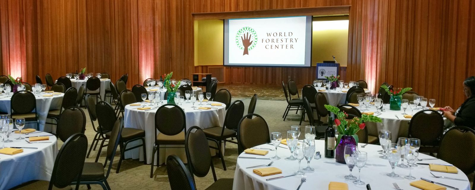 banquet setting in an event space with a large screen set for a conference