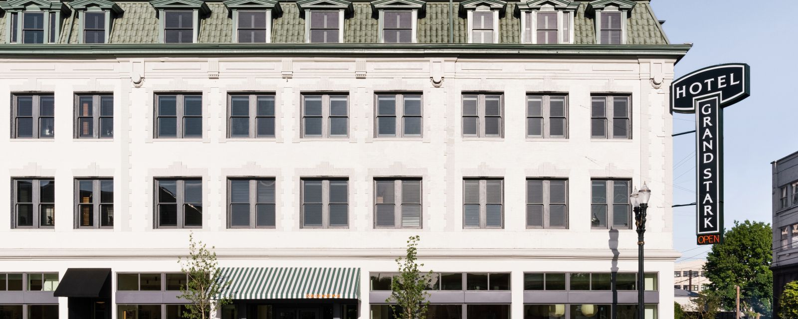 the exterior view of a hotel with a green tiled roof and a large sign saying Hotel Grand Stark