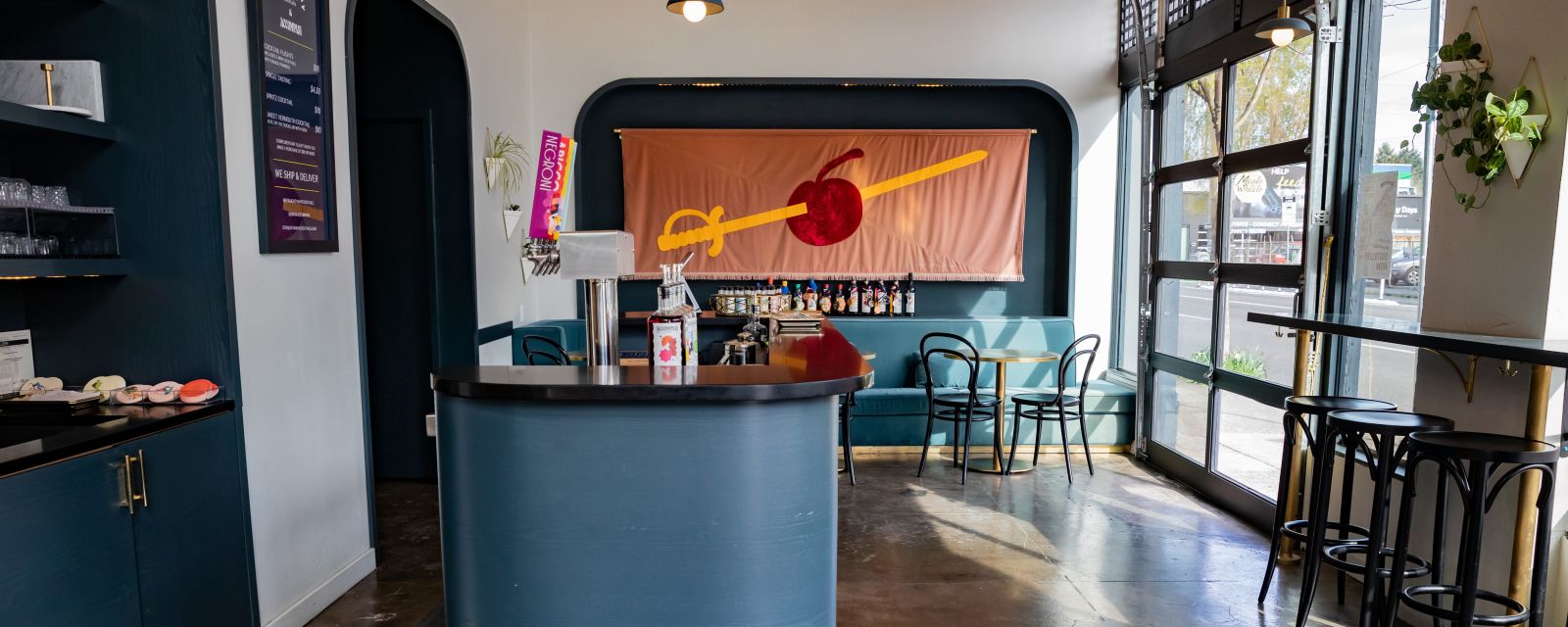 a cocktail tasting room with a bar, stools, a large glass door and colorful decor