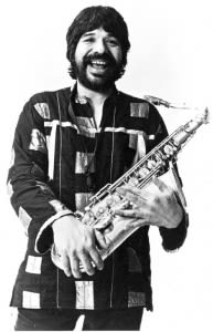 A smiling man holding a saxaphone