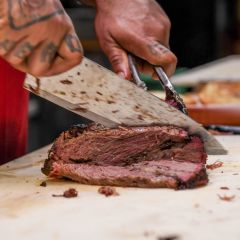 a close-up of a chef cutting slices of juicy brisket