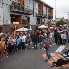 crowd gathered around a street musician as he performs at Last Thursday art walk