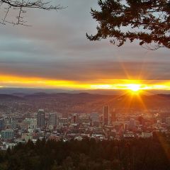 the sun rising behind a view of downtown Portland