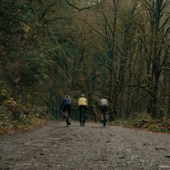 three cyclists ride on a muddy gravel path in Forest Park