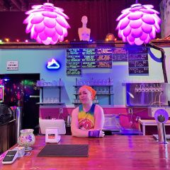 purple lights illuminate a person standing behind a bar at a gluten free brewery