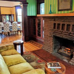 couch in front of a fireplace with the view of a dinning room in a bed and breakfast