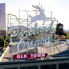 cityscape with a high rise in the background and the White Stag Portland Oregon Old Town sign in the foreground