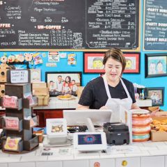A cashier works behind the counter at a doughnut shot.
