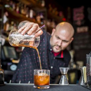 Man pouring mixed drink in to glass