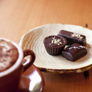 dish of truffle chocolates next to a mug of coffee on a wooden coffee table