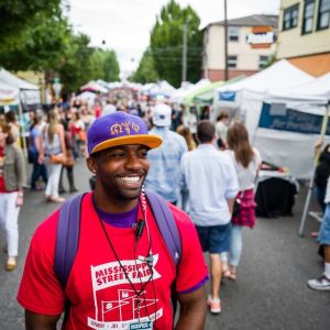 a crowd explores a city street lined with vendor pop-up tents